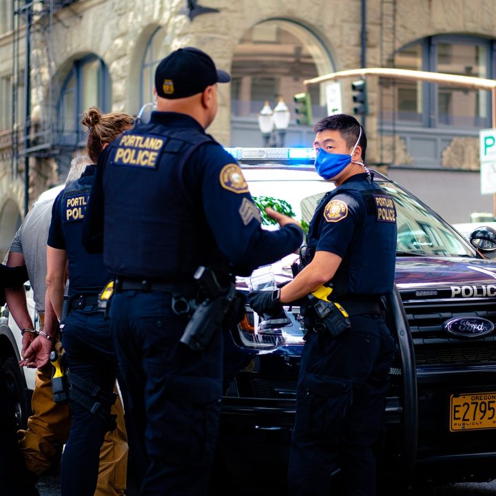 Un grupo de policías de Portland en la calle junto a un auto policial.