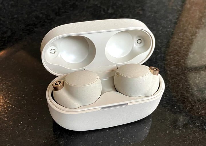 Auriculares Sony WF-1000XM4 blancos en su estuche sobre una superficie oscura.