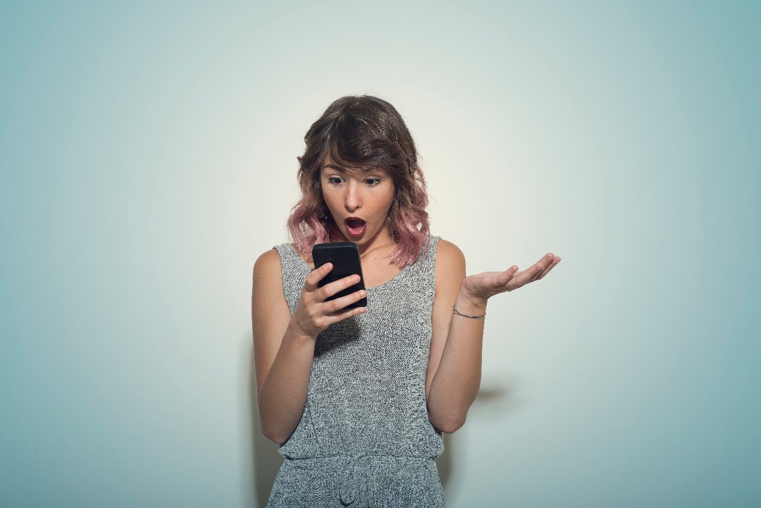 Una mujer revisa su teléfono con cara de sorpresa