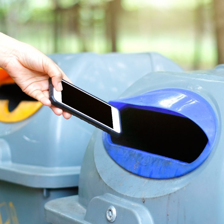 Una persona deposita un teléfono en un buzón de reciclaje