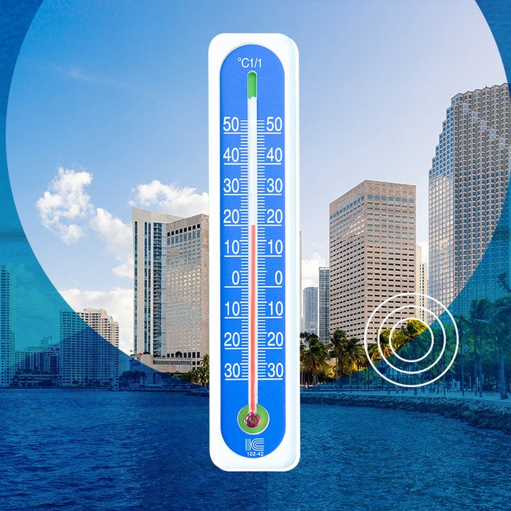 Un termómetro de temperatura ambiente sobre una postal de Miami.