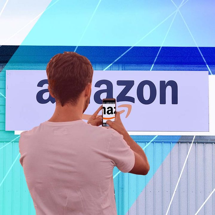 Una persona con su celular apuntando hacia el logo de Amazon.