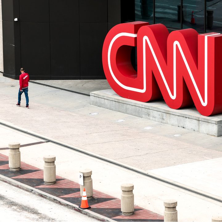 Un hombre camina frente al logo gigante de CNN