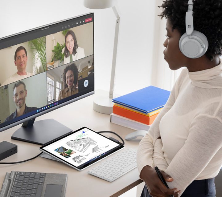 Una mujer con audifonos frente a una computadora.