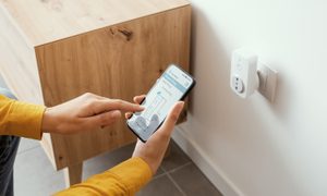 Persona configurando un enchufe inteligente con su celular – Enchufes inteligentes: esto es todo lo que necesitas saber.