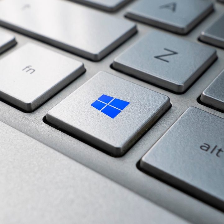 Teclado de computadora con el logo de Windows en azul sobre una tecla – Windows 11 vs. Windows 10: ¿deberías actualizarte?