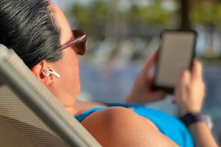 Mujer con AirPods mirando su celular.