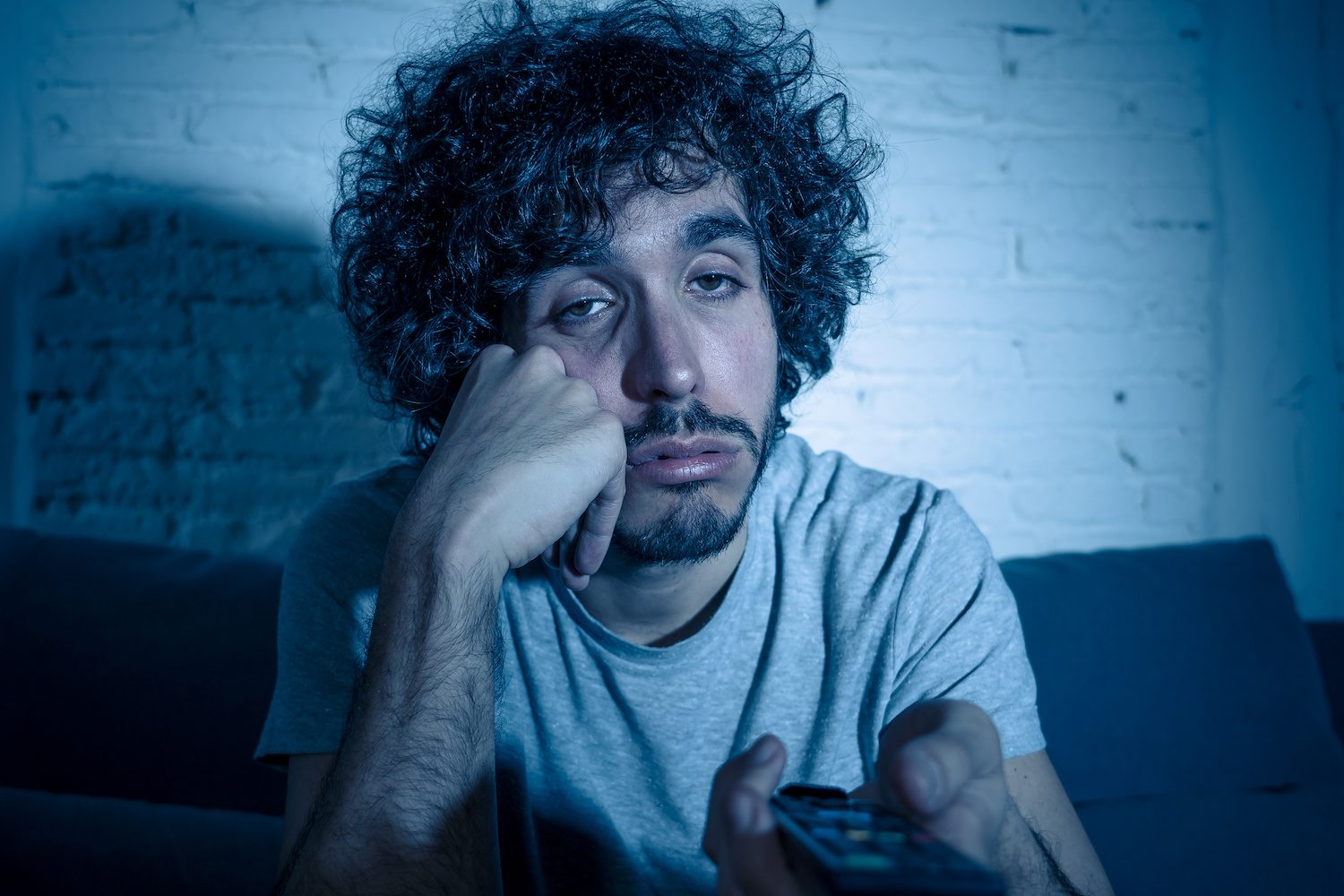 Hombre aburrido viendo televisión – Cómo cancelar tu suscripción a Disney Plus rápidamente.