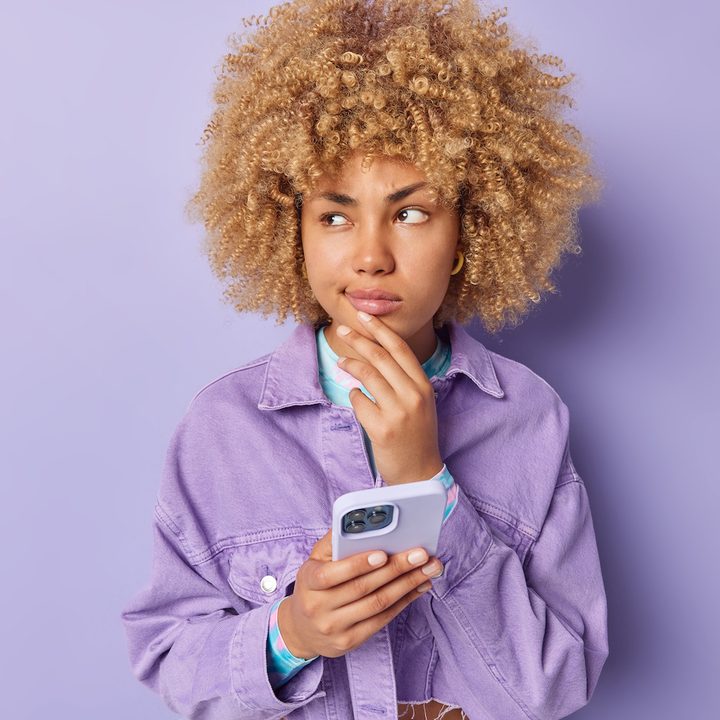 Chica joven y pensativa con un celular en la mano – El ojo público todo lo ve, y esto es un aspecto que define a las redes sociales. No tienes que ser un actor o un músico famoso: tu vida queda expuesta al resto del mundo cada vez que publicas una foto en Instagram.