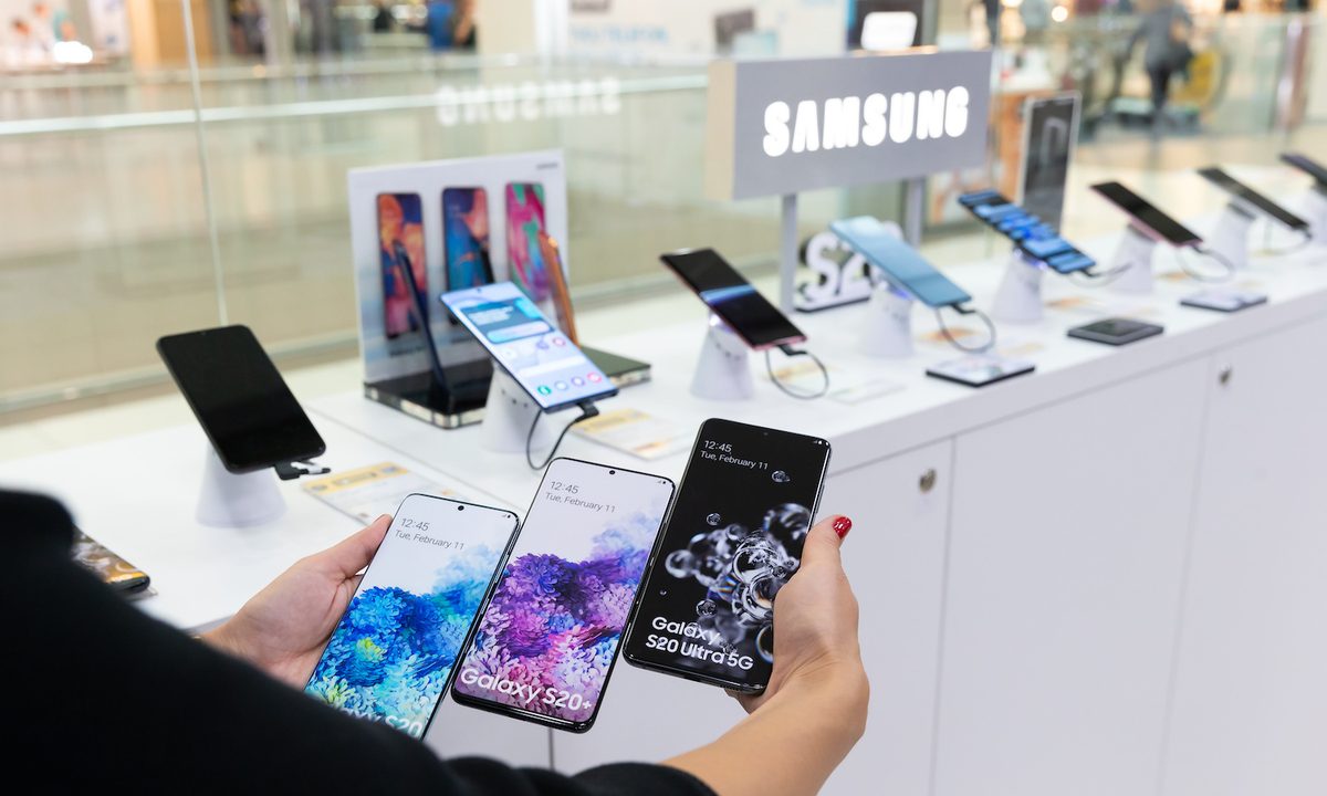 Persona mostrando tres teléfonos Samsung en una tienda – Estas son las diferencias entre los celulares Samsung Galaxy S, A, J y M.