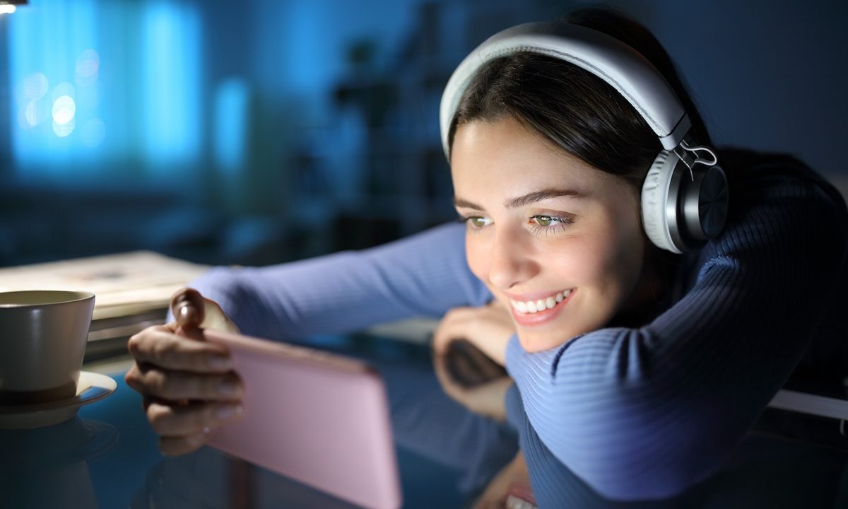 Mujer joven viendo videos en su celular – Las 13 mejores apps para ver series y películas gratis desde el celular.