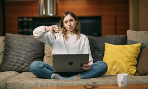 Mujer joven con una laptop y haciendo el pulgar hacia abajo – Cómo desinstalar Windows 11