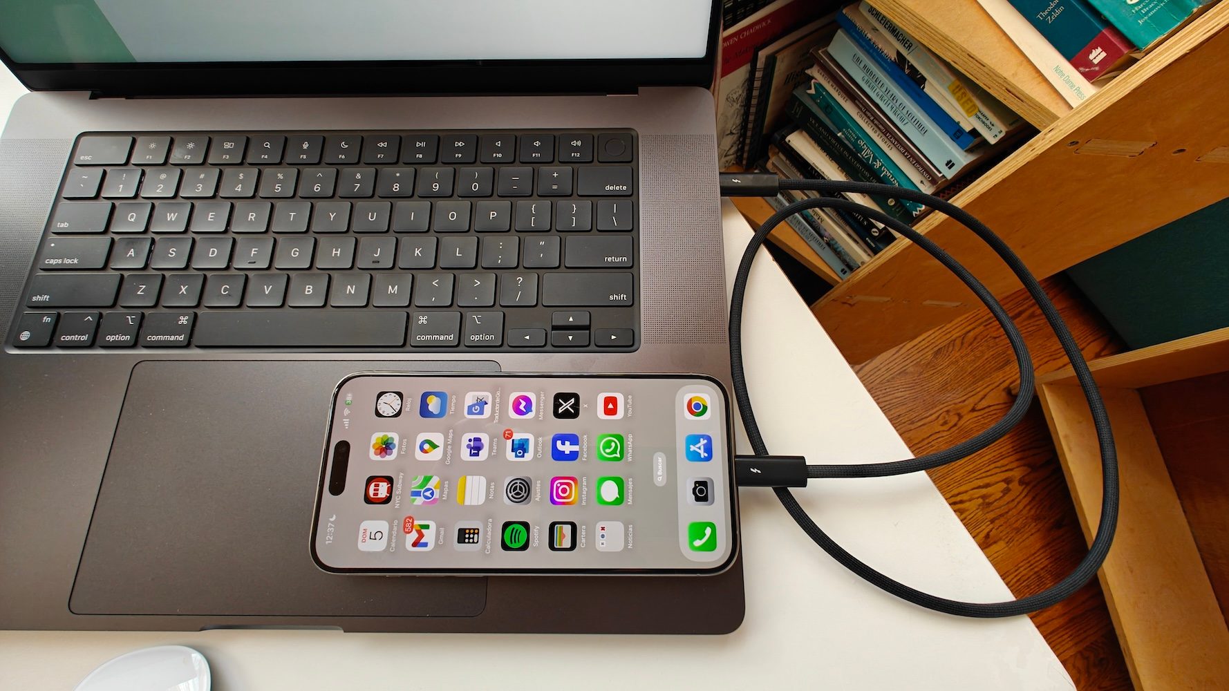 MacBook Pro 16 M3 Max y iPhone 15 Pro Max conectados mediante un cable Thunderbolt 4.