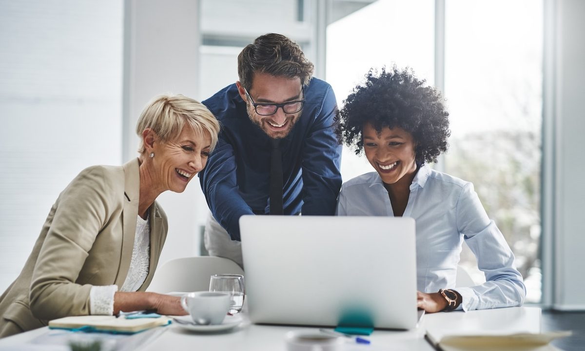 Tres personas felices frente a la pantalla de un ordenador– Cómo grabar la pantalla de tu computador.