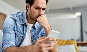Un hombre preocupado sosteniendo su celular.