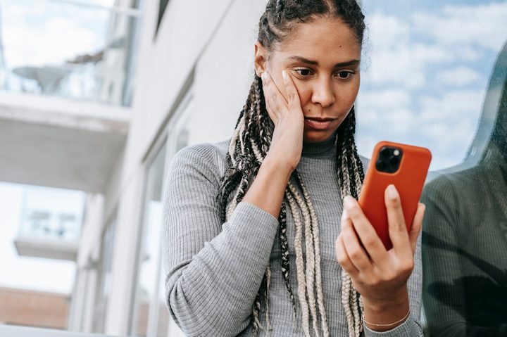 Una mujer preocupada mirando su celular.