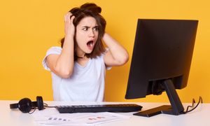 Mujer enojada mirando a una pantalla de un computador. Por qué la PC se apaga sola