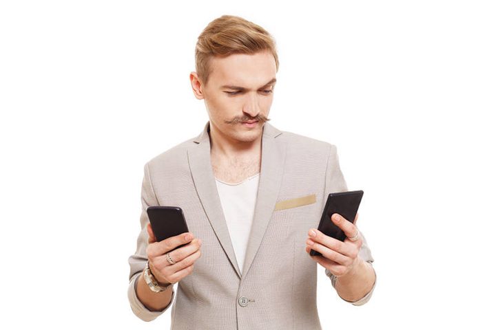 Hombre sosteniendo dos teléfonos.