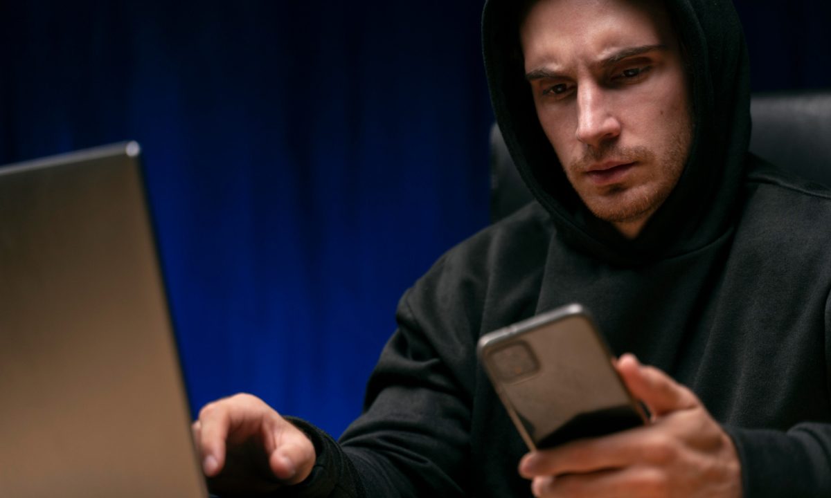 Phishing. Hombre preocupado mirando su celular y su computadora.