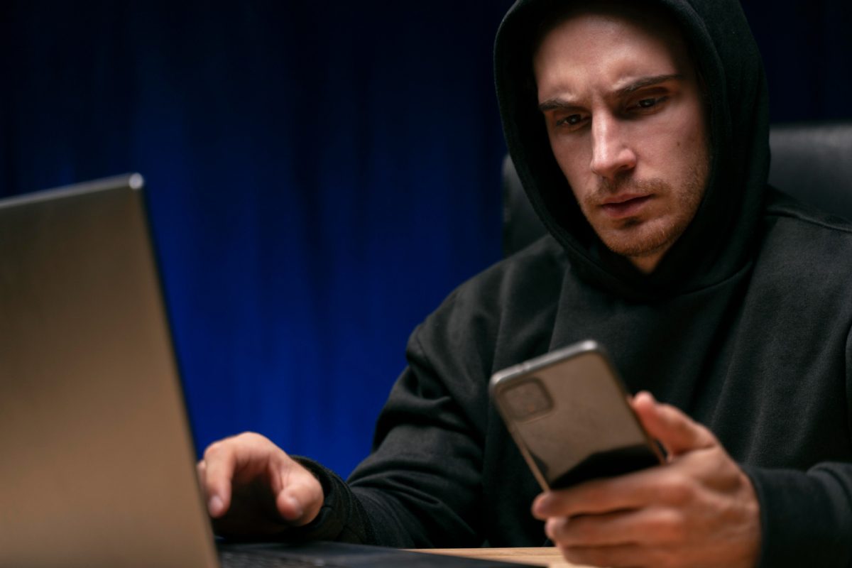 Phishing. Hombre preocupado mirando su celular y su computadora.