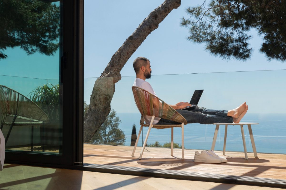 Hombre trabajando en una laptop desde un balcón