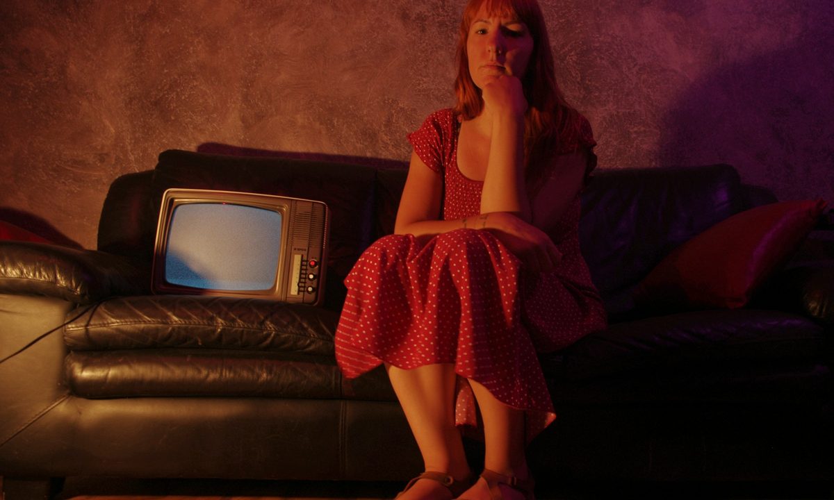 Mujer sentada al lado de un televisor