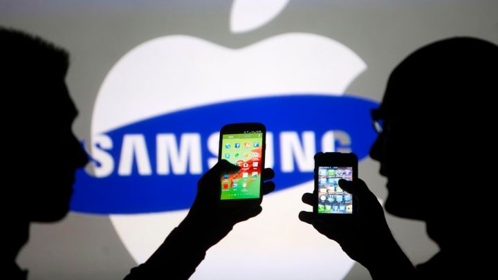apple contrata empleados de samsung y periodistas expertos en musica men pose with galaxy s3 and iphone 4 smartphones in phot