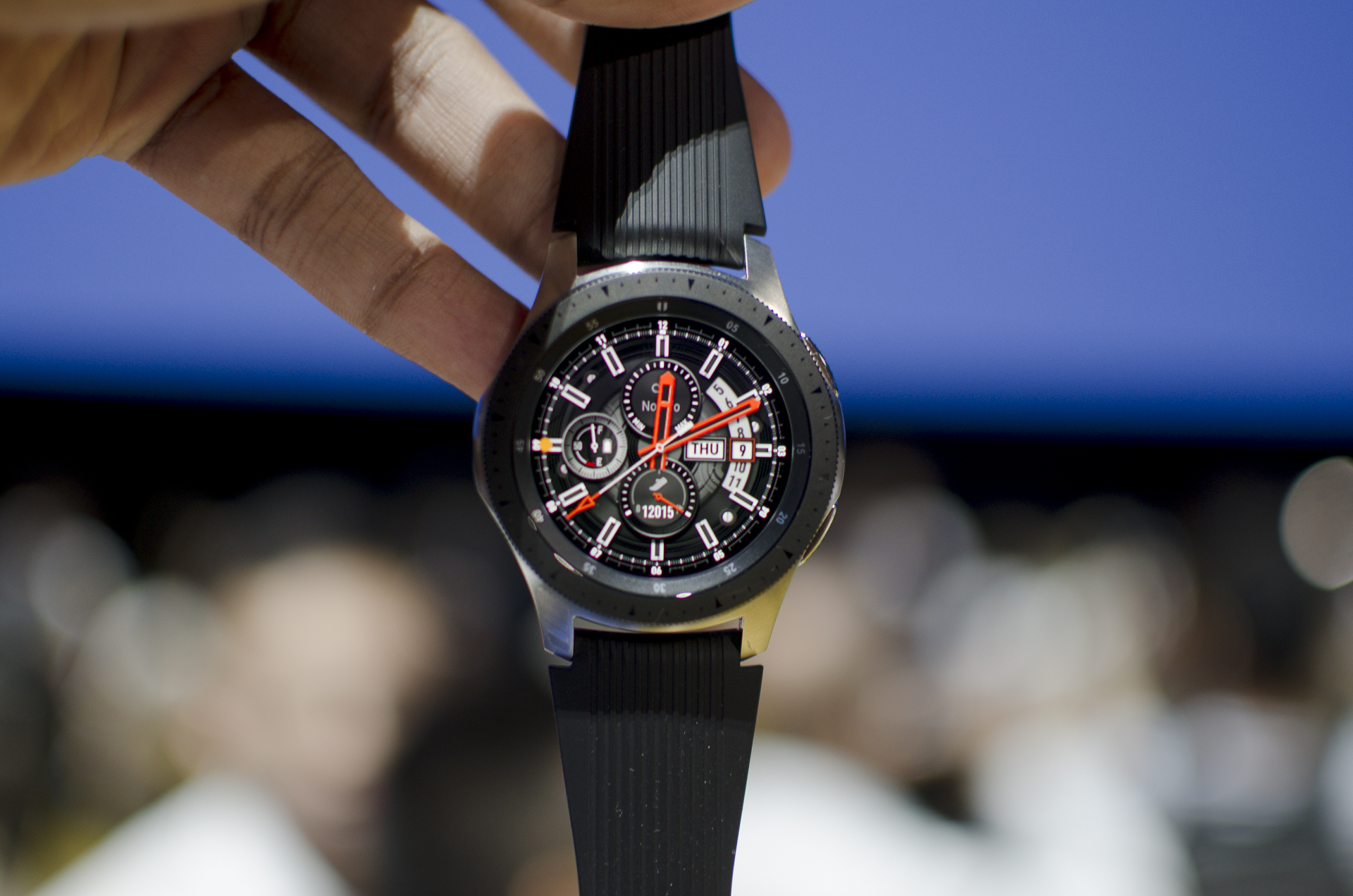 Una mano sostiene desde sus correas el Galaxy Watch