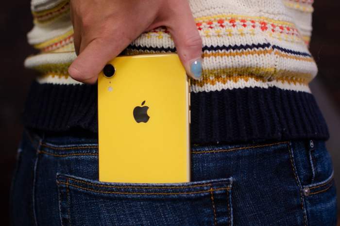 teléfono de apple amarillo entrando en el bolsillo de un pantalón