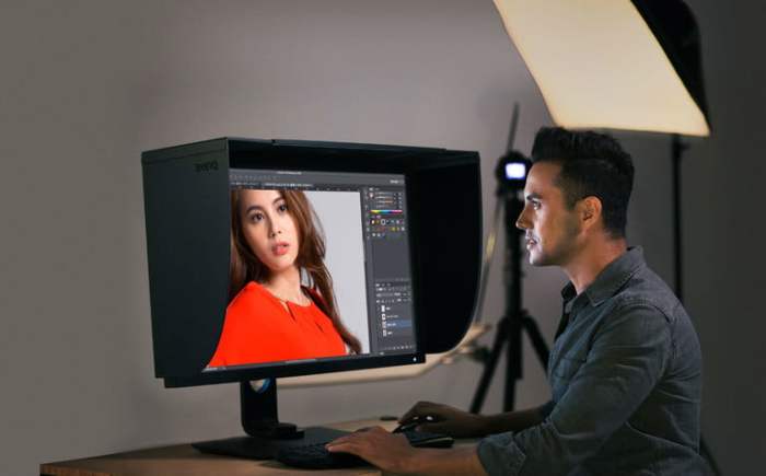 un hombre sentado frente a un monitor que tiene una fotografía en plano medio de una mujer