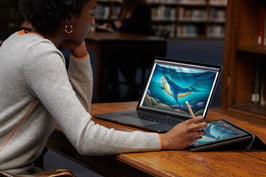 mujer mirando un laptop mientras dibuja en una iPad