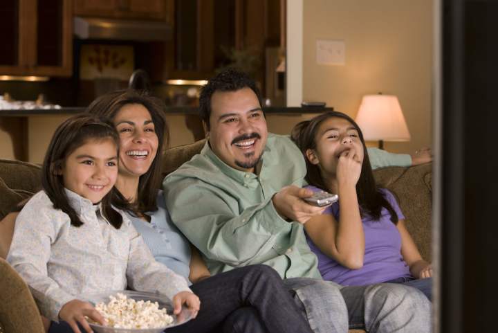 Una familia viendo un video despues de aprender a convertir VHS a DVD y otros formatos