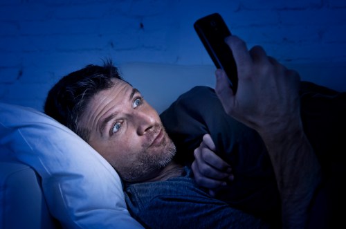hombre mirando su teléfono en la noche