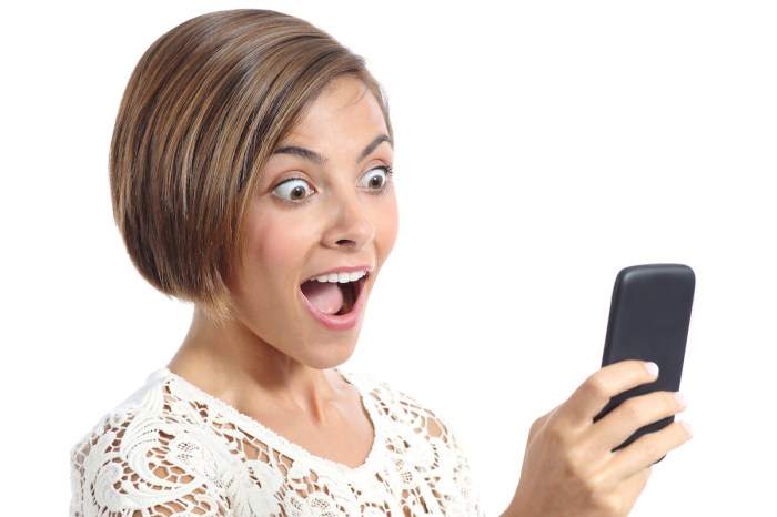 Mujer viendo su teléfono con expresión de sorpresa