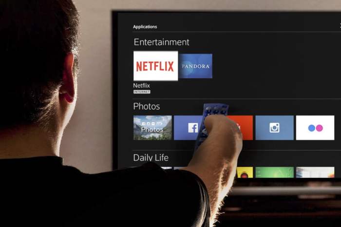 Una persona apunta a la pantalla de su televisor con su control remoto para explicar cómo usar Netflix Party