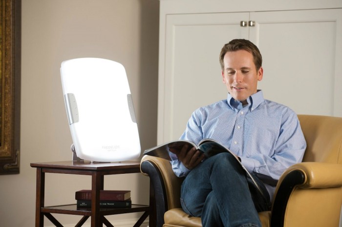 hombre leyendo junto a una lámpara de terapia
