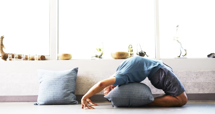 A man does yoga in the living room of his house with one of the best meditation apps
