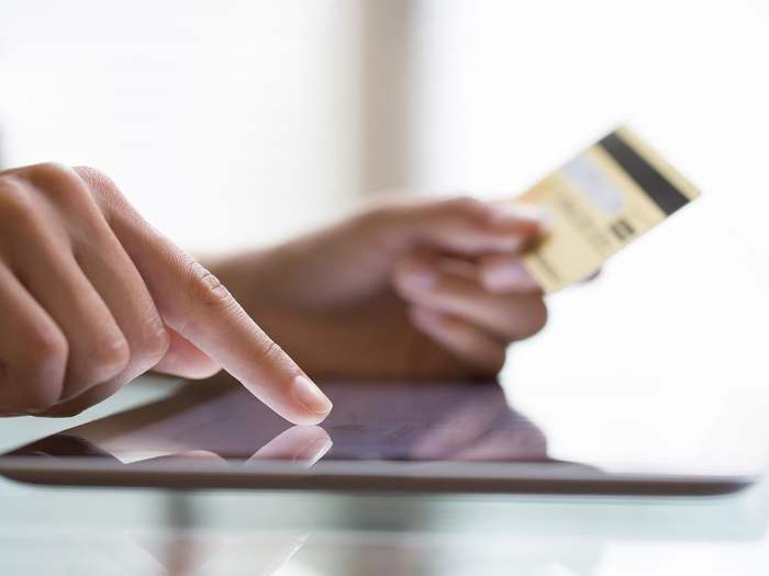 Una persona realiza una compra con su tarjeta de crédito a través de una tableta.