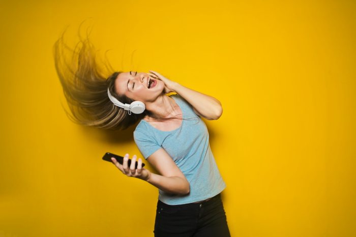 Mujer bailando con auriculares conectados a su celular, porque pudo agregar música al iphone