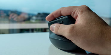 Logitech MX Vertical el mejor ratón ergonómico en la mano de una persona trabajando sobre un escritorio