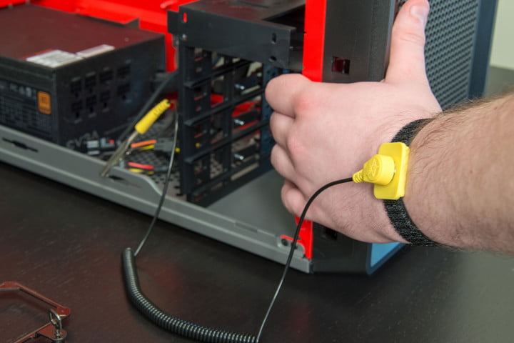 Mano de un hombre con una pulsera antiestatica agarrando el gabinete de una computadora