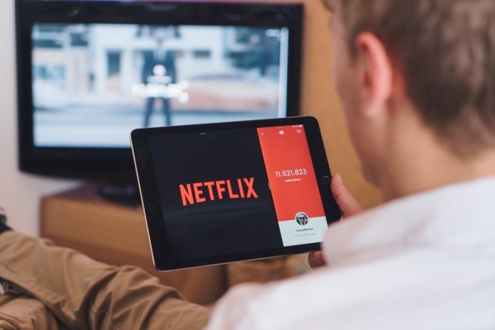 Una persona sostiene una tableta con el logo de Netflix para investigar cuánto cuesta Netflix