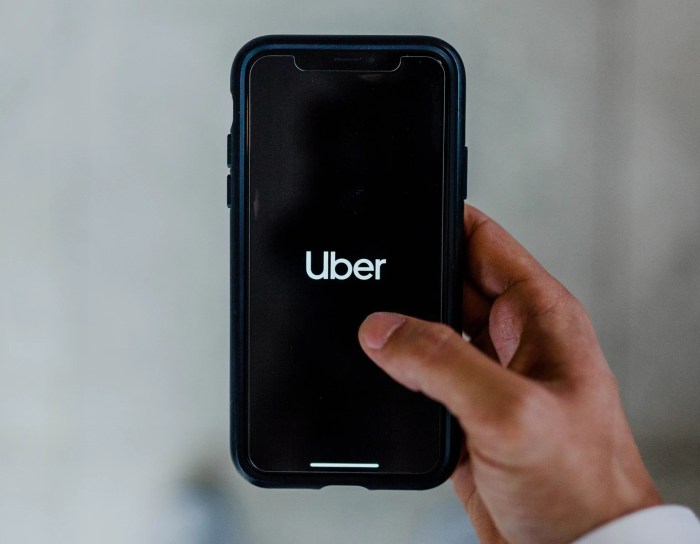 Una persona sostiene un teléfono celular con el logo de Uber