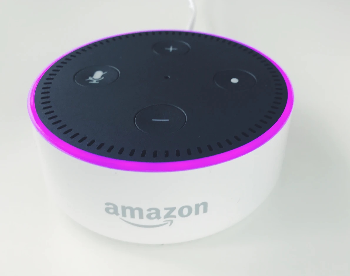 Un altavoz Echo Dot 2 de color blanco y luces lilas sobre un escritorio