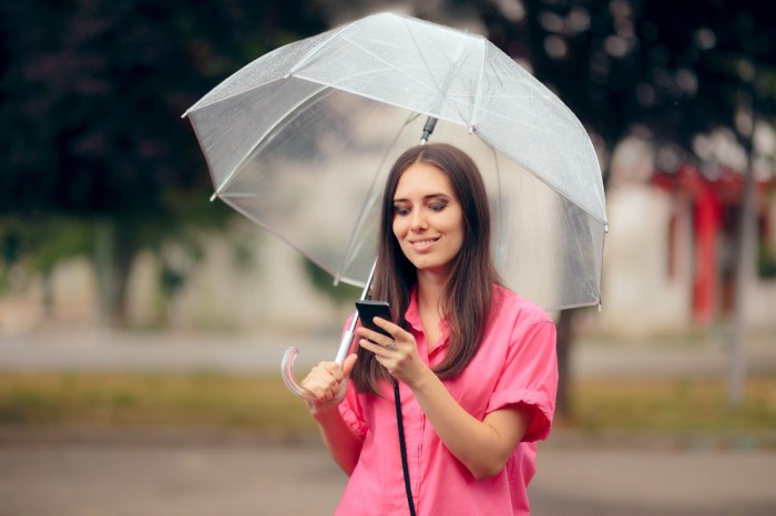 Mujer con paraguas viendo su teléfono - aplicaciones clima Android