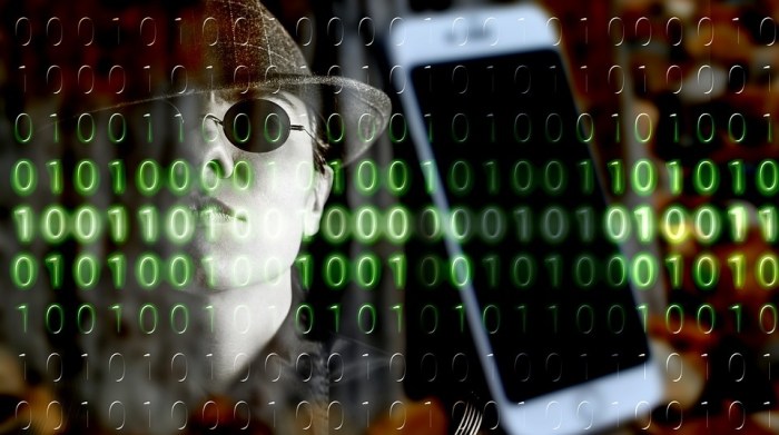 Una persona de fondo y un teléfono móvil con códigos binarios de color verde asemejando un hackeo