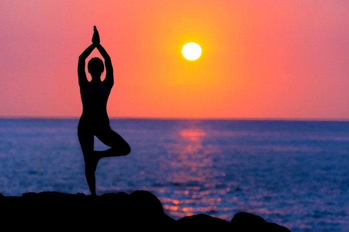 foto que muestra una mujer practicando yoga al atardecer frente al mar y con una bella puesta de sol