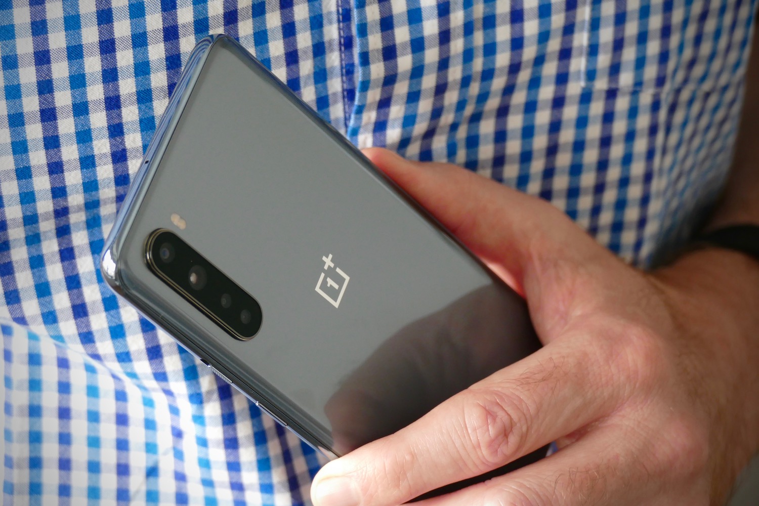 una mano sujeta un OnePlus Nord de color gris visto por la parte trasera