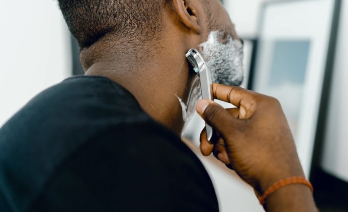 Una persona se afeita frente al espejo con una maquinillas de afeitar desechable
