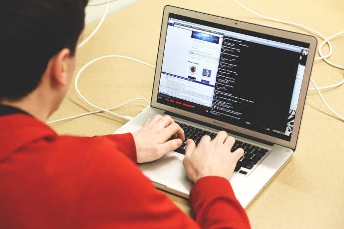 un hombre sentado con sus manos en el teclado de una laptop